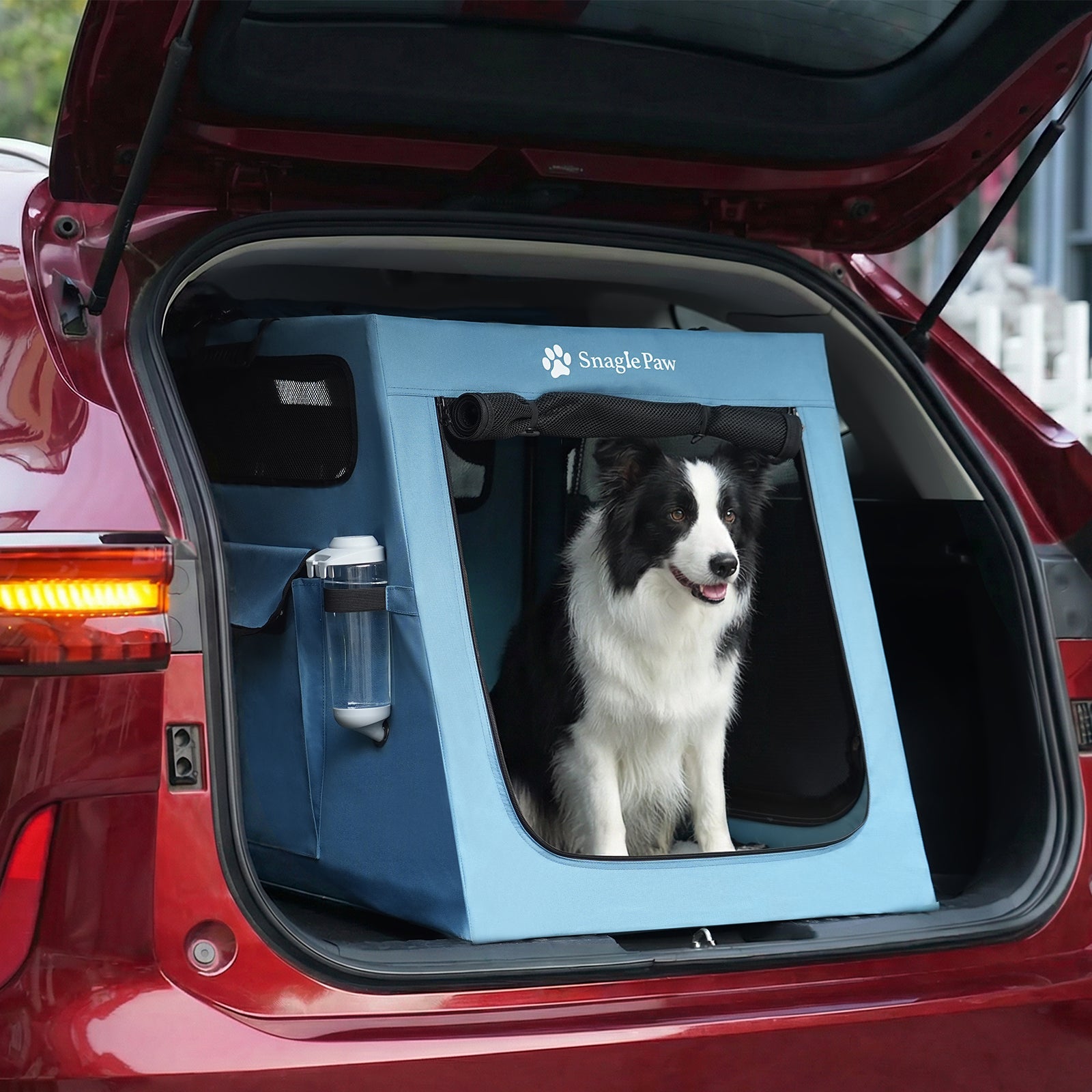 Side view of Snagle Paw dog crate in a red SUV trunk, highlighting the built-in water bottle holder and side pockets.